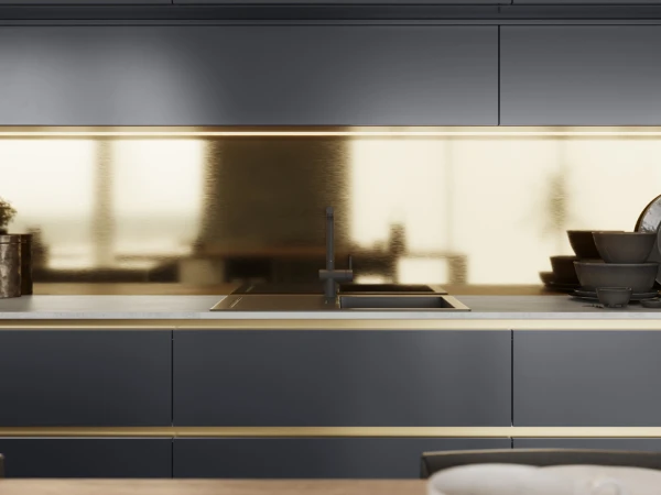 Modern minimalist kitchen with dark grey cabinetry, white countertop, built-in sink with black tap, and cream-coloured illuminated backsplash, with stacked bowls and decorative items on the counter