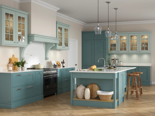 Modern kitchen with turquoise cabinetry, white countertops and curved range hood, featuring glass-front upper cabinets, a central island with white marble top and open storage, three pendant lights, wooden bar stools, herringbone wood flooring, and decorative accessories including fresh flowers and kitchenware throughout the space.