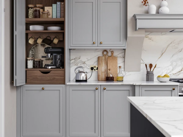 Modern kitchen with grey cabinetry featuring an open wooden shelving unit displaying cookware, dishes and pantry items, marble countertops, brass hardware, and a stainless steel kettle and wooden chopping boards on the counter.