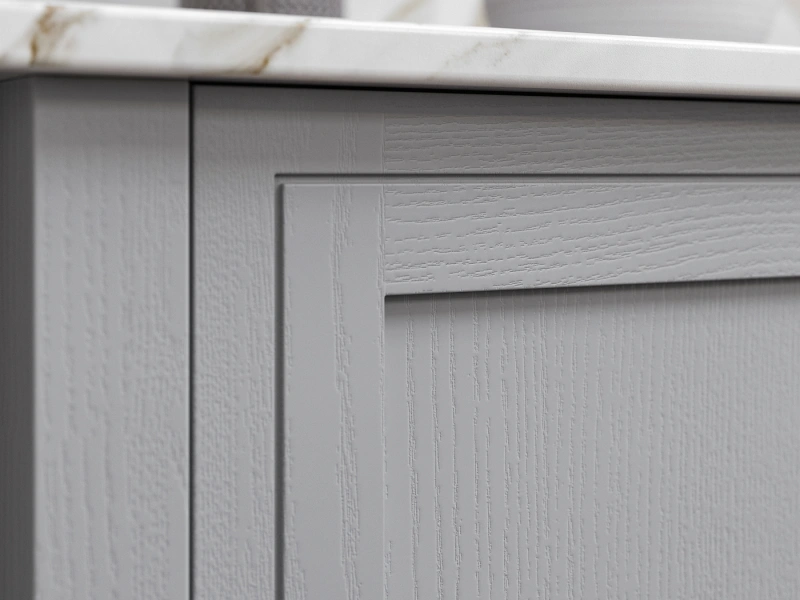 Close-up of white kitchen cabinet doors with textured wood grain finish and marble countertop edge visible at top