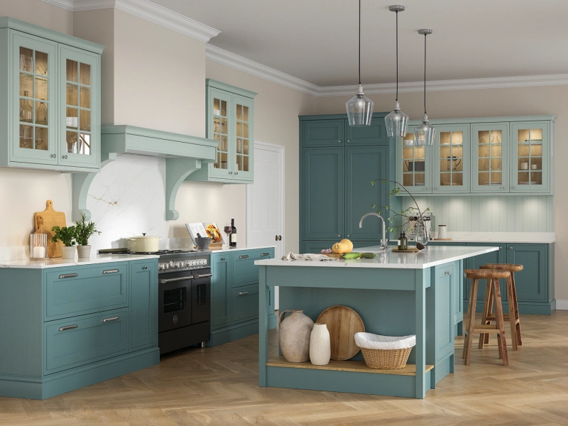 Modern kitchen with turquoise cabinetry, white countertops and curved range hood, featuring glass-front upper cabinets, a central island with white marble top and open storage, three pendant lights, wooden bar stools, herringbone wood flooring, and decorative accessories including fresh flowers and kitchenware throughout the space.
