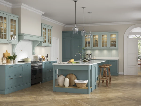 A modern kitchen with soft blue cabinetry, white worktops, pendant lighting, and a central island with seating.