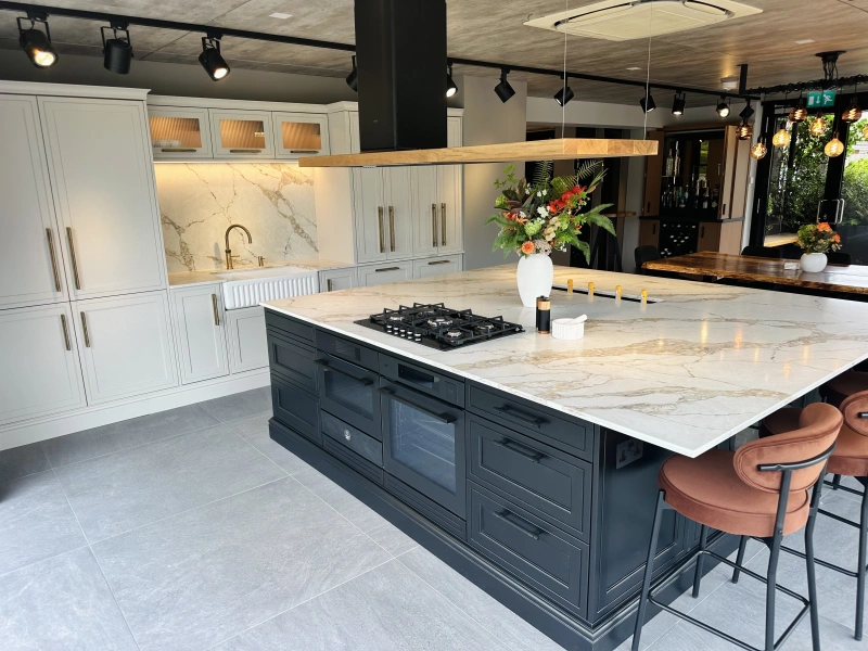 Modern kitchen showroom with white and black cabinetry, marble countertops, and island seating.