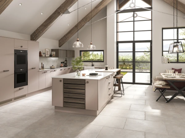 Modern kitchen with pale cabinetry, island, exposed beams, and open-plan living area with large windows.
