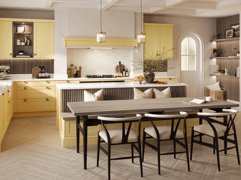 Modern kitchen and dining space with yellow cabinetry, marble backsplash, and white coffered ceiling featuring a central island with seating, pendant lighting, and a wooden dining table with black chairs positioned in the foreground.