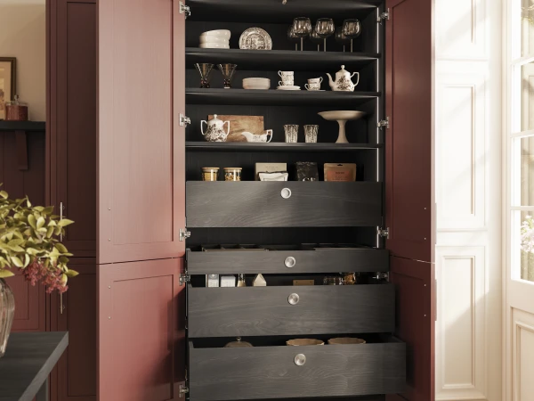 Burgundy cabinet with open doors displaying shelves of dishware and glassware, with dark drawers below.