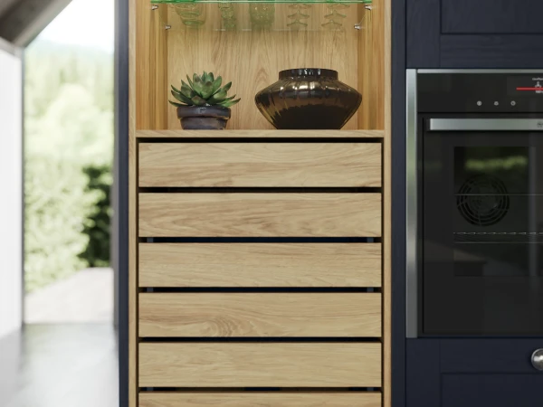 Tall wooden storage unit with glass shelves displaying glassware and a plant, drawers below, integrated into modern kitchen.