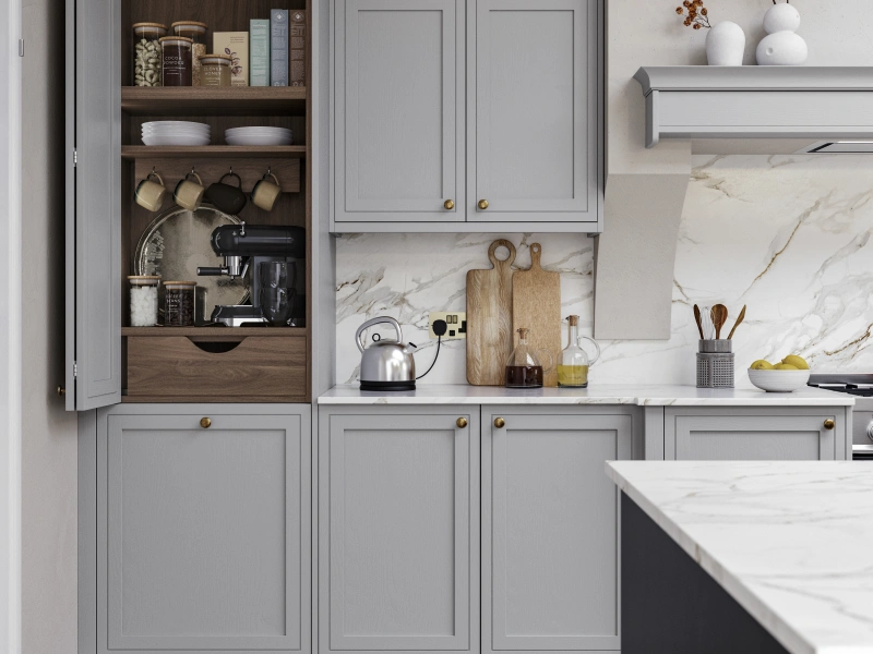 Gray kitchen cabinetry with open shelving, marble backsplash, and brass hardware in a modern showroom display.