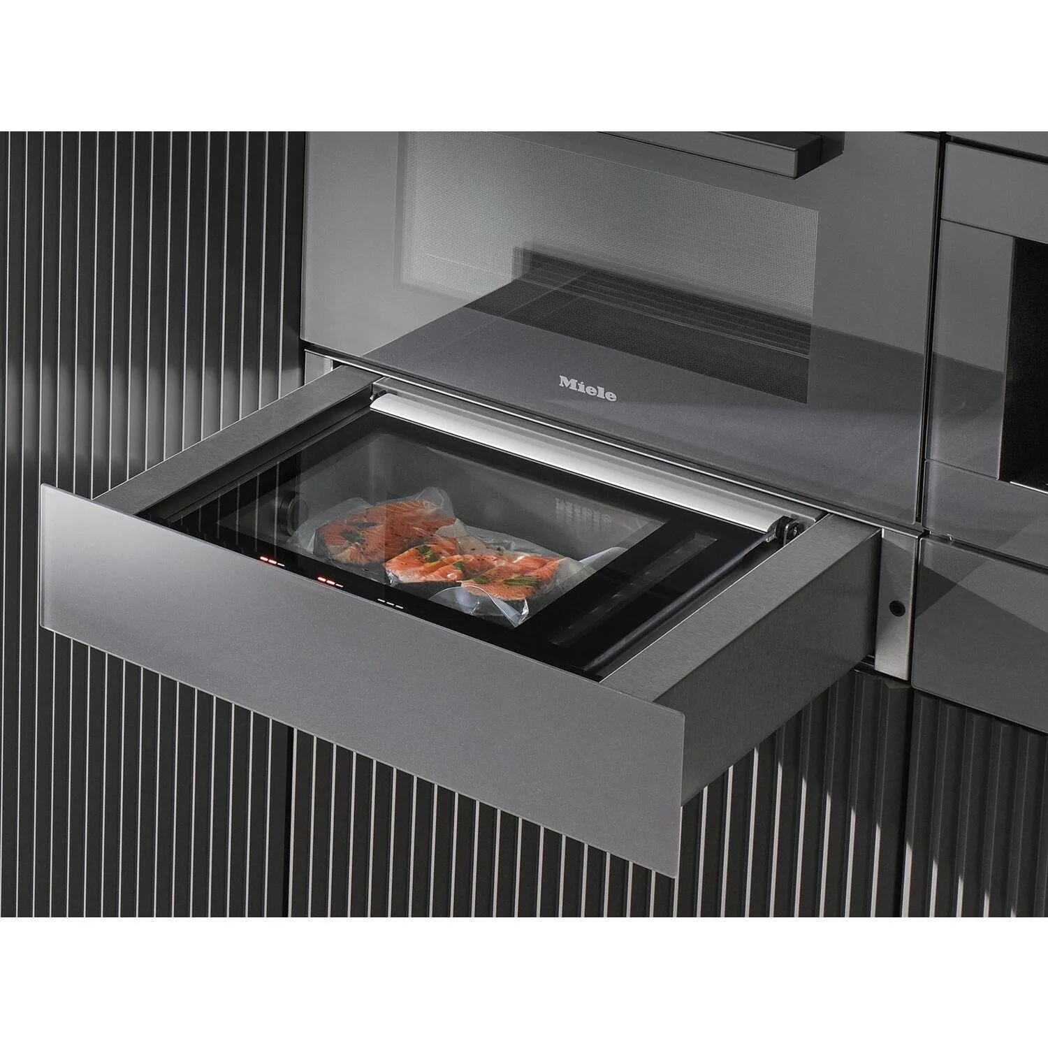 Miele steam oven drawer pulled open showing packaged salmon fillets inside the cooking chamber, with a microwave above in a modern kitchen cabinet with vertical ribbed panelling
