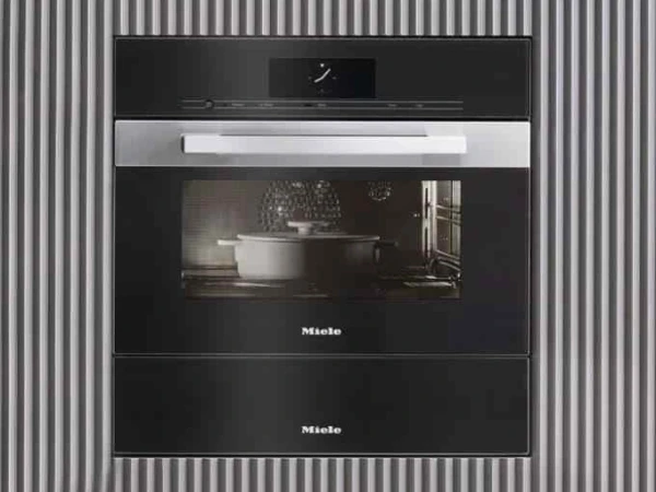 Miele built-in compact oven with steam function and microwave combined unit, featuring a black and stainless steel design mounted into a corrugated metal wall