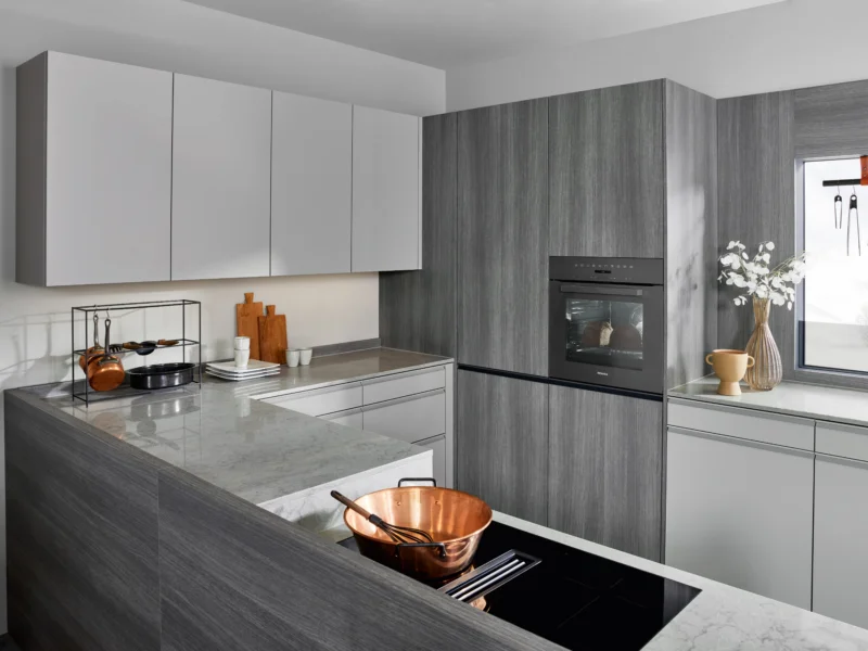 Modern kitchen with white and dark grey cabinetry, marble countertops, and integrated appliances.