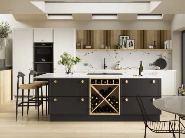 Modern kitchen with white cabinetry and black island featuring built-in wine rack, white marble backsplash, wooden slat wall panelling with open shelving, integrated black appliances, two bar stools with woven seats, wooden flooring, recessed ceiling lights, fresh greenery, and large windows overlooking garden area