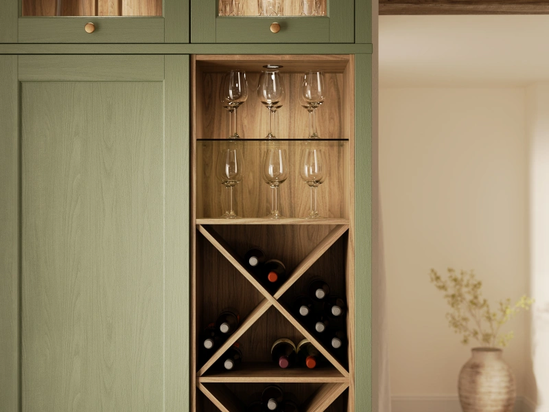 Green cabinetry with integrated wooden wine and glass storage display unit.