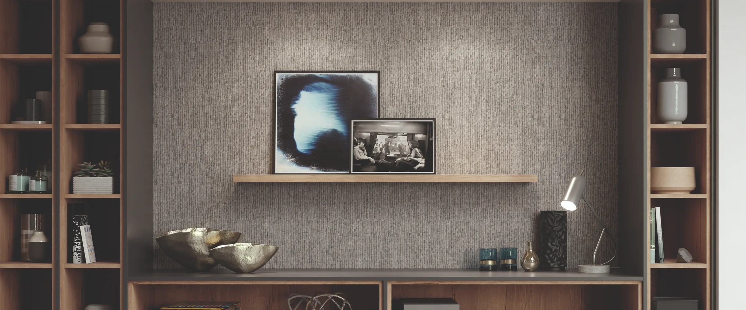 Modern interior design featuring wall-mounted wooden shelving units and cabinets with decorative items, framed artworks displayed on a floating shelf, a white desk lamp, and a textured grey wall backdrop.