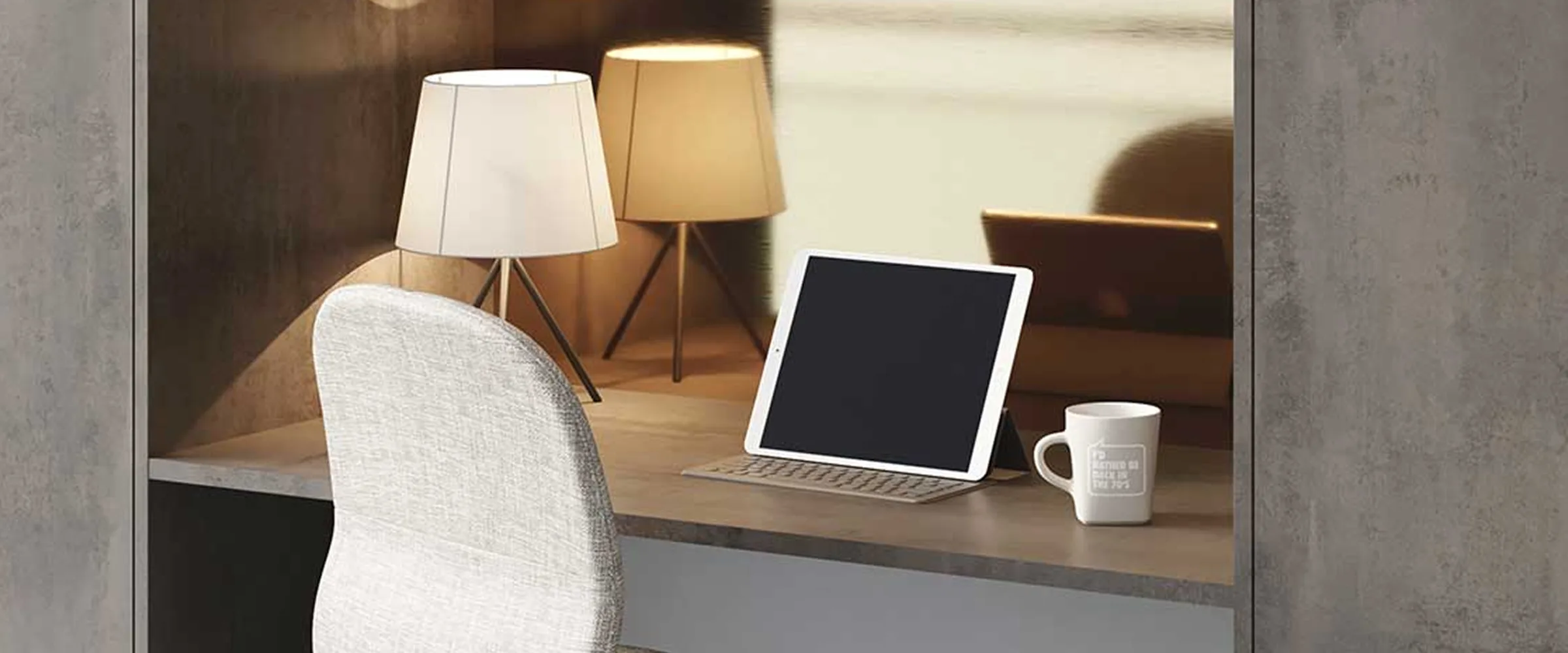 Modern office workspace with a white upholstered chair, wooden desk holding a tablet with keyboard and white mug, illuminated by two tripod table lamps with white and tan shades, against a concrete wall background.