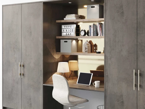 Built-in home office nook with concrete grey cabinetry, wooden shelves displaying books and decorative items, a lightbox reading "HAVE A NICE DAY", desk with tablet and lamp, and a white upholstered chair, flanked by tall storage cabinets on either side.
