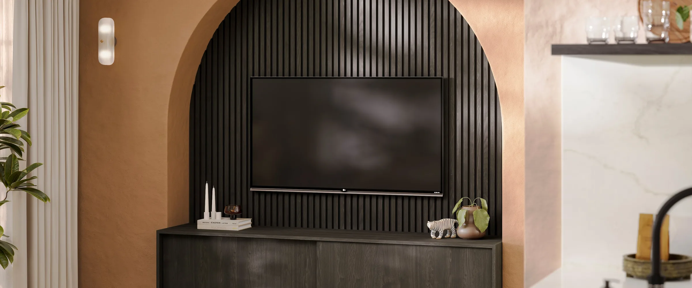 Modern living room with arched niche featuring wall-mounted television, black vertical slat accent wall, dark wooden console table with decorative items including candles, books and potted plant, warm beige curved walls, and cream curtains on the left side