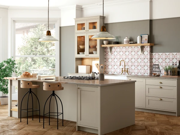 Modern kitchen with cream-coloured cabinetry, grey half-painted walls, and pink geometric patterned backsplash, featuring a central island with wooden bar stools, pendant lights, open shelving, and a large window overlooking green foliage.