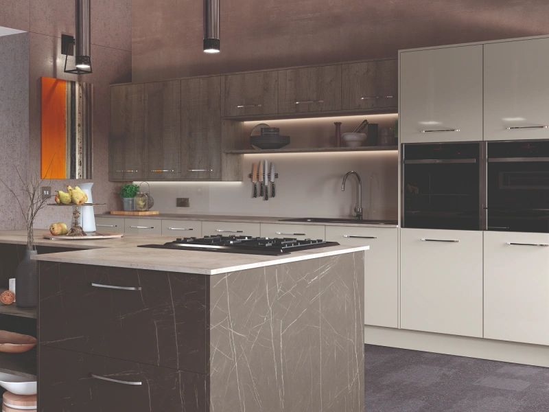 Modern kitchen interior with dark marble-effect island featuring a gas hob, light beige cabinetry, dark upper cabinets with illuminated shelving, stainless steel appliances, pendant lighting, and minimalist décor with orange accents.