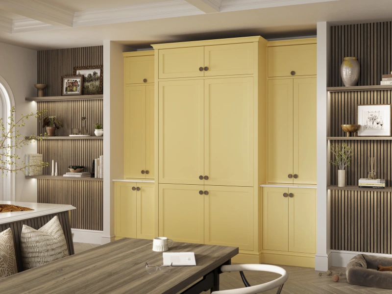 Modern living room interior with large yellow built-in wardrobes featuring multiple compartments and dark handles, flanked by grey ribbed wall panelling and shelving units displaying decorative items, a round archway entrance, wooden flooring, and contemporary furniture including a dining table and upholstered seating