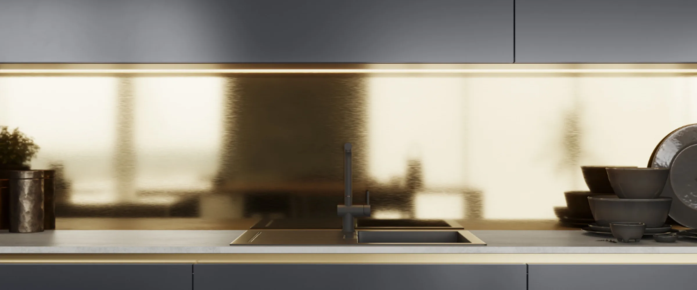 Modern kitchen countertop with stainless steel sink and black tap fixture, white backsplash with brass trim, dark cabinetry below, and decorative items including stacked bowls and a container on either side of the sink