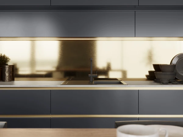 Modern kitchen interior with dark grey cabinetry, brass-trimmed shelving, integrated sink with black tap, stacked black bowls, potted plant, and warm natural light from window, with white mug in foreground